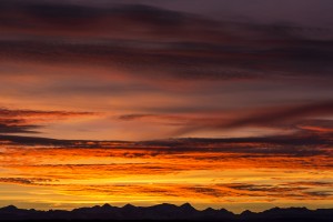 Colourful dramatic clouds at sunset with silhouette of mountains along the horizon; Calgary, Alberta, Canada