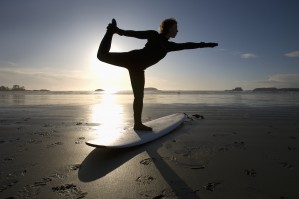Silhouette Of Female Surfer Doing Bow Pulling Yoga Pose; Chesterman Beach Tofino Vancouver Island British Columbia Canada
