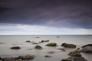 Rocks in tranquil water under storm clouds;Northumberland england