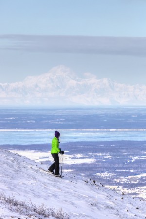 Woman snowshoeing on Blueberry Hill at the Glen Alps area of Chugach State Park with Mt. McKinley (Denali) in the background, Anchorage, Southcentral Alaska, Winter, HDR