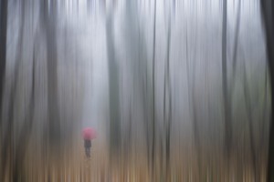 A woman walking with a red umbrella as viewed through a sheer curtain;Ronco sopra ascona ticino switzerland