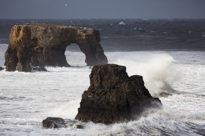 Rock formations and a natural arch in the ocean with splashing waves;South Shields Tyne and Wear England