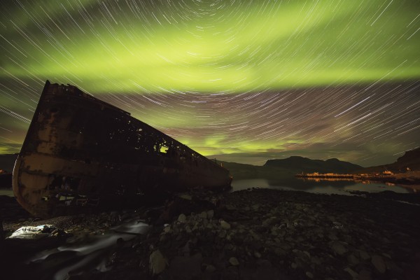 Star trails and northern lights over top the town of Djupavik in the West Fjords of Iceland; Djupavik, Iceland by PacificStock