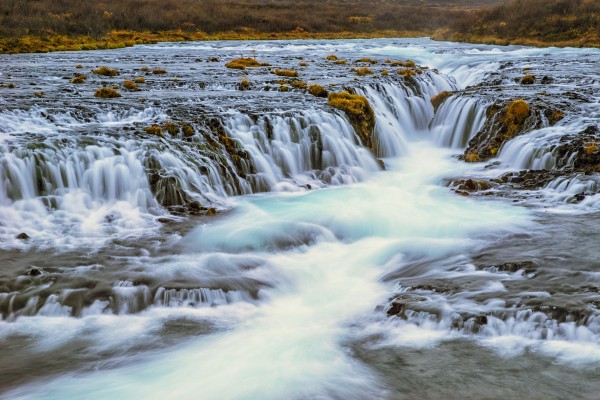 Water cascading over rocks and flowing into a river; Bruarfoss, Iceland by PacificStock