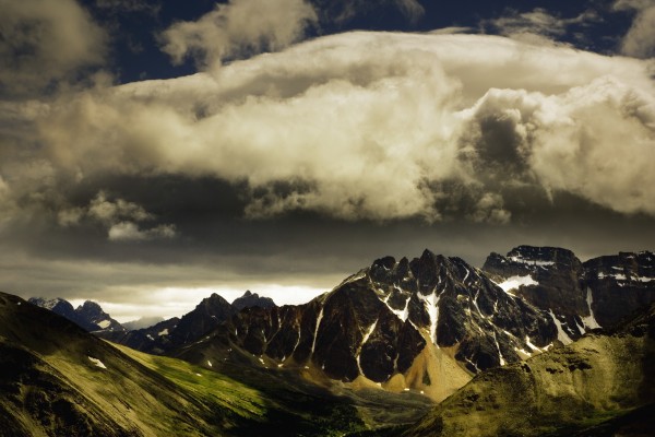 Patches Of Light Find Their Way Through Hovering Clouds Above Mountain Range by PacificStock