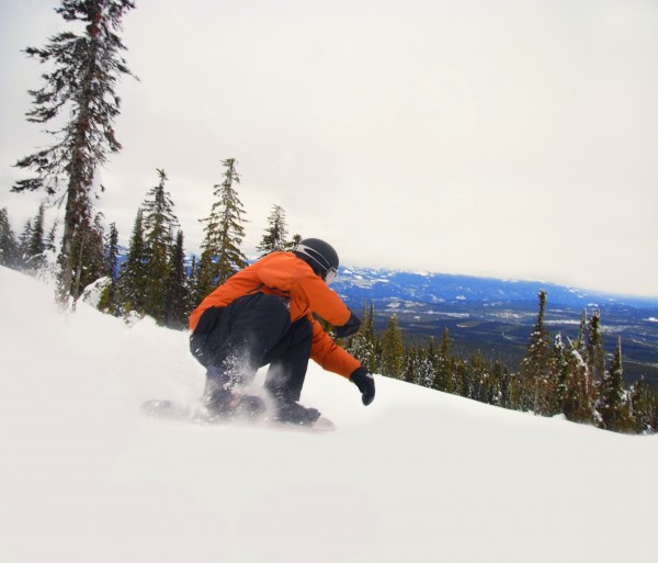 Snowboarder Crouching Down Low As He Descends Snow Hill by PacificStock