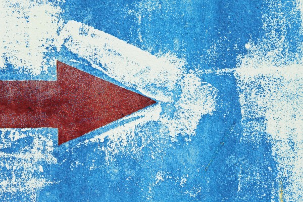 Red Arrow Painted On Blue Wall by PacificStock