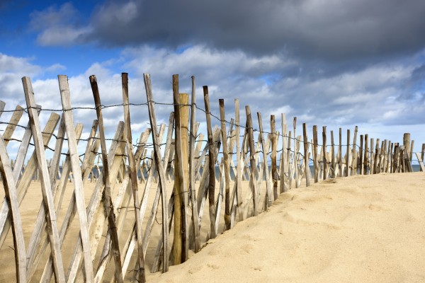 South Shields, Tyne And Wear, England; Dark Clouds Over Fence On A Beach by PacificStock