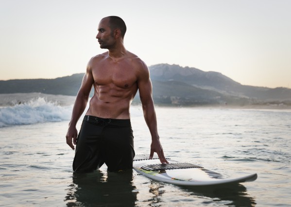 A Man Standing In The Water With His Surfboard Off Valdevaqueros Beach; Tarifa, Cadiz, Andalusia, Spain by PacificStock