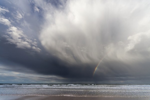 A Rainbow In The Dark Clouds Over The Ocean; Bamburgh, England by PacificStock