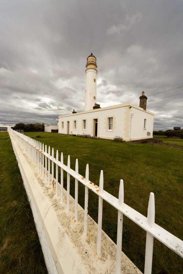 A White Fence Beside Barns Ness Lighthouse; Lothian, Scotland by PacificStock