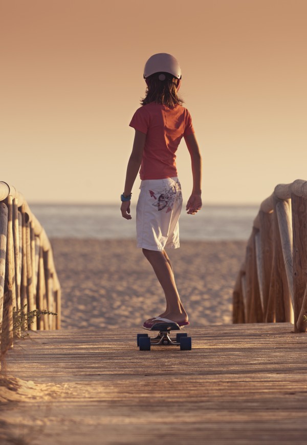 A Young Person Skateboarding With Bare Feet Over A Wooden Boardwalk Towards The Beach; Tarifa, Cadiz, Andalusia, Spain by PacificStock