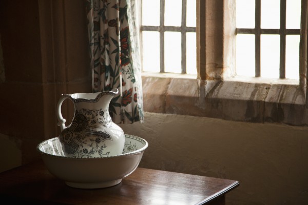 A Pitcher And Basin Sit On The Table Beside A Window; Lindisfarne, Northumberland, England by PacificStock