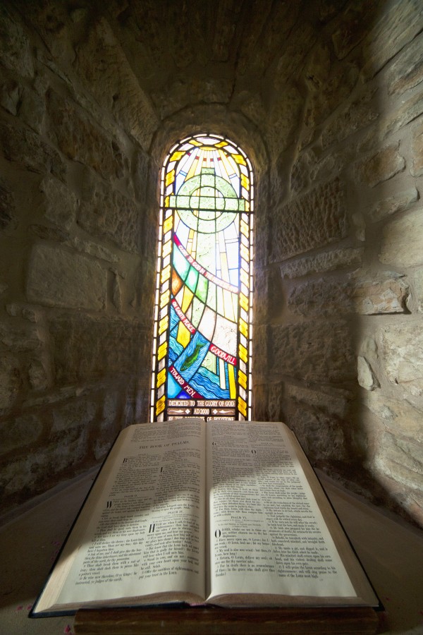 An Open Bible And A Stained Glass Window In St. Mary's Church; Holystone, Northumberland, England by PacificStock