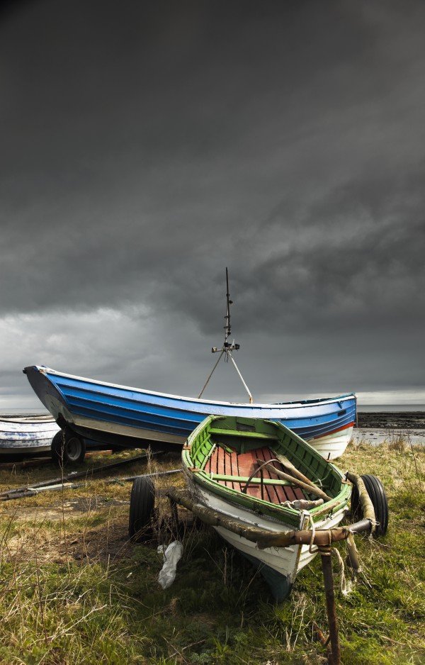 Rowboats sitting on trailers on the shore under storm clouds;Boulmer northumberland england by PacificStock