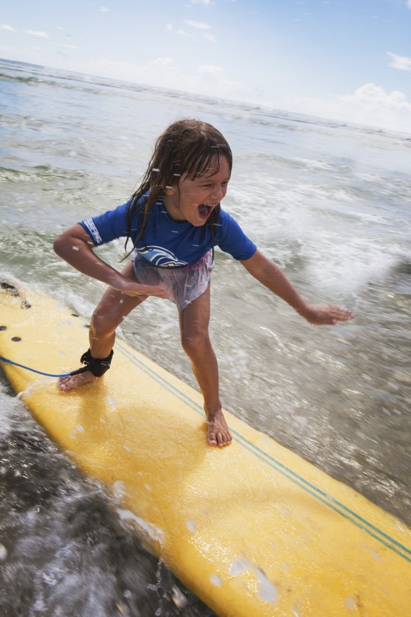 A young girl on a yellow surfboard;Gold coast queensland australia by PacificStock