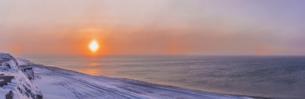 Sunset through windblown snow creates a sundog above the Beaufort Sea along the coast just outside of Barrow, Winter, Arctic Alaska, USA. by PacificStock