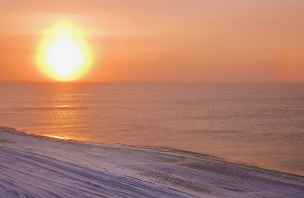 Sunset through windblown snow creates a sundog above the Beaufort Sea along the coast just outside of Barrow, Winter, Arctic Alaska, USA. by PacificStock