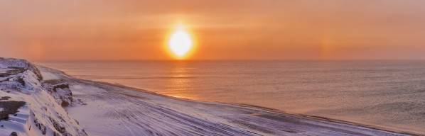 Sunset through windblown snow creates a sundog above the Beaufort Sea along the coast just outside of Barrow, Winter, Arctic Alaska, USA. by PacificStock