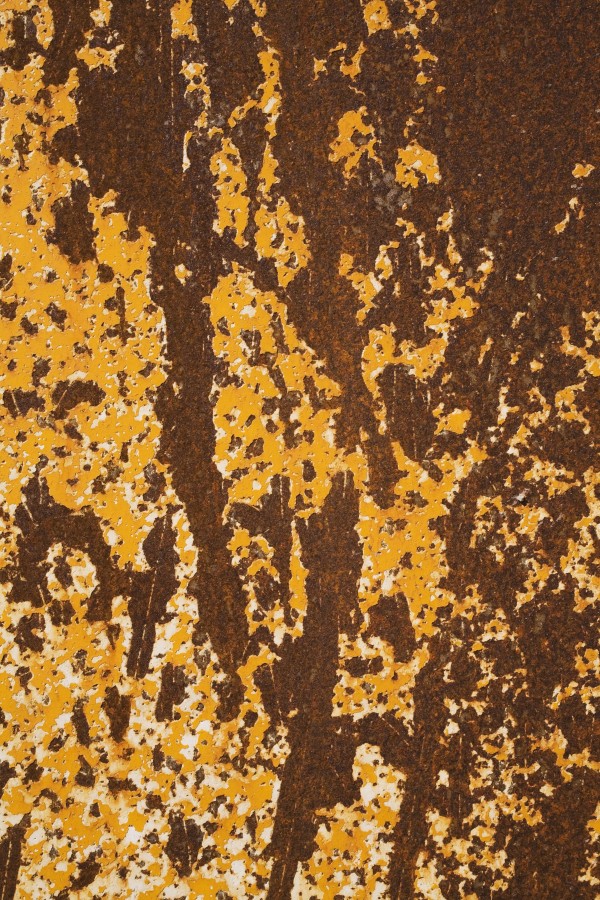 Close up of peeling yellow paint and rust patterns on a ferous metal surface;Laval quebec canada by PacificStock