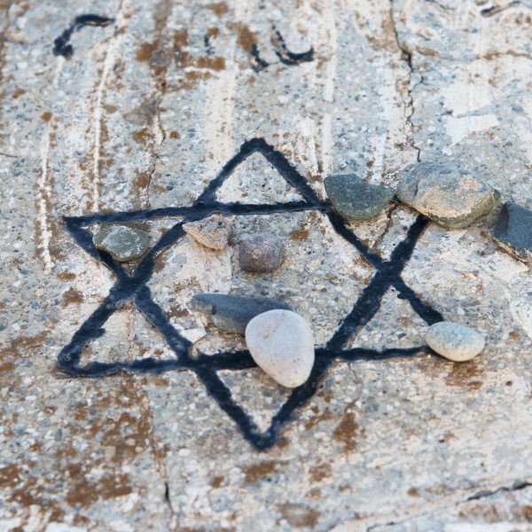 A star of david etched and painted on a rock with stones laying on it Print