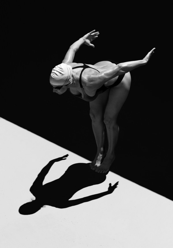 A Woman Prepares To Jump Backwards Off The Edge Of A Pool Into The Water; Tarifa, Cadiz, Andalusia, Spain by PacificStock