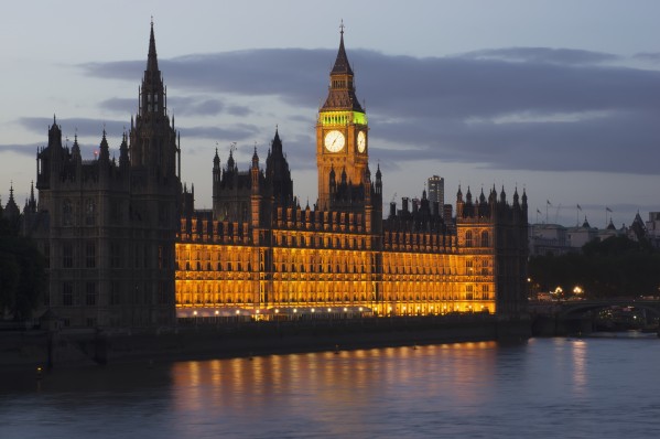 A Building And Clock Tower Along The Water's Edge Illuminated At Dusk; London, England by PacificStock