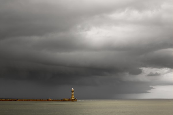 Lighthouse at the end of a pier with dark storm clouds overhead; Sunderland, Tyne and Wear, England by PacificStock