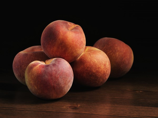 Peaches sitting on a wooden table; Montreal, Quebec, Canada by PacificStock