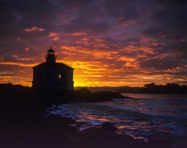 The sun rises behind the Coquille River Lighthouse; Bandon, Oregon, United States of America by PacificStock