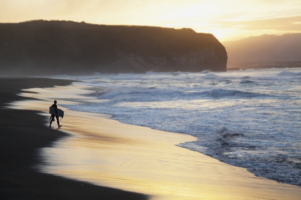 A surfer walks to the water at sunrise, Santa Barbara Island; Sao Miguel Island, Acores, Portugal by PacificStock