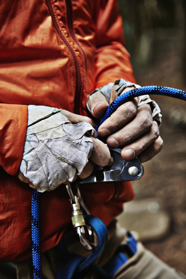 Man adjusting rock climbing equipment in the Adirondacks; New York, USA by PacificStock