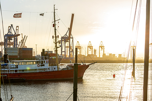 Historic boats in the old harbor in Hamburg at the Elbe River at sunset