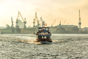 Harbor ferry on the Elbe River in front of docks and container terminals in Hamburg Germany