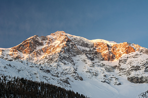Orange light of the sunrise reaching the top of the Ortler Mountain in South Tyrol 