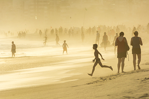 Boy running towards the ocean at Ipanema Beach in Rio de Janeiro during dramatic sunset