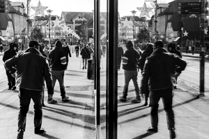 Black and white street photo of people being reflected in a shop window