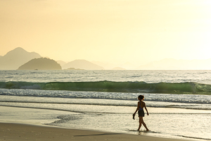 Woman walking along Copacabana Beach in Rio de Janeiro in Brazil at sunrise 