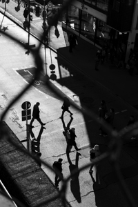 Black and white street photo of people crossing a road in the city 