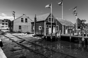 Black and white shot of historic harbour buildings and boat ramp on Cape Cod in New England 