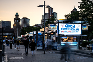 Hamburg Germany – 06 18 2025: Long exposure night shot of people strolling along the pier at St. Pauli Landungsbrücken at the Elbe River
