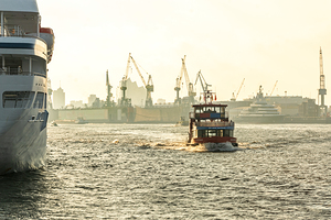 Harbor ferry cruising alongside a large cruise ship on the Elbe River in Hamburg 