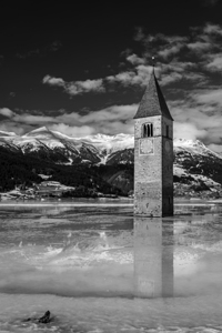 Black and white shot of the flooded bell tower in Lake Reschen Reschensee in South Tyrol