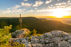 Beautiful sunset over a rock ledge and summit cross Wackerstein in the Swabian Alps in Southern Germany