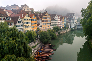 Traditional punt boats Stocherkahn in front of picturesque buildings at the waterfront of Tübingen in the morning fog 