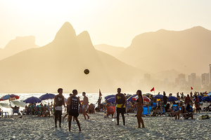 Young people playing football at Ipanema Beach in Rio de Janeiro during beautiful sunset 