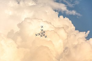 Fighter jets flying in a triangle formation during airshow in scenic clouds