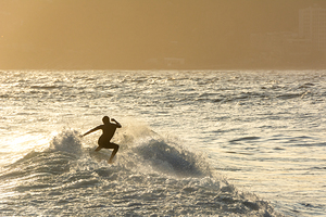 Surfer riding the waves at sunset at Ipanema Beach in Rio de Janeiro in Brazil
