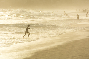 Boy running through the water at Ipanema Beach in Rio de Janeiro in Brazil at sunset  