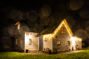 Charmingly illuminated cosy traditional thatched roof house in Northern Germany at night 